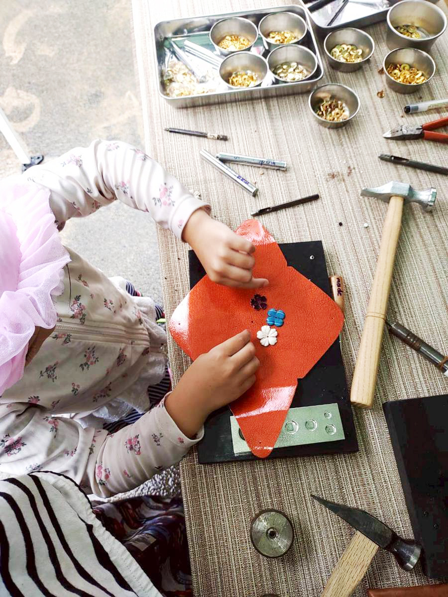 革に花のパーツを付ける子どもの制作体験